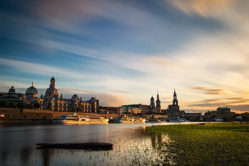 Symbolbild: Dresdner Altstadt mit Frauenkirche und Hofkirche an der Elbe bei Sonnenuntergang.