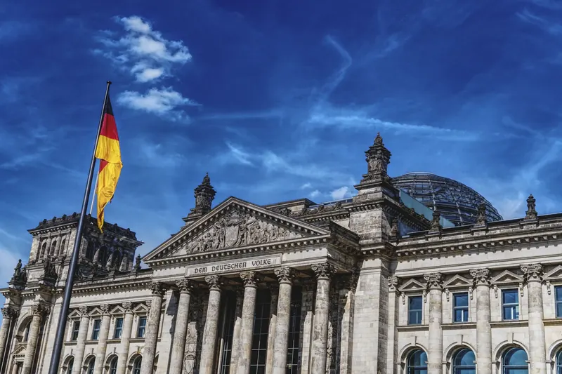 Symbolbild: Reichstagsgebäude in Berlin mit Inschrift „Dem deutschen Volke“ und Deutschlandfahne.