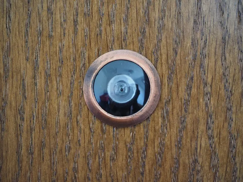 Symbolbild: Türspion in einer hölzernen Wohnungstür